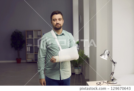 Portrait of young man with broken arm in sling 129670643