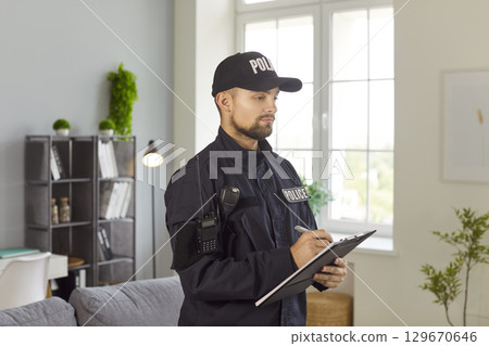 Police officer writing report during home investigation visit 129670646