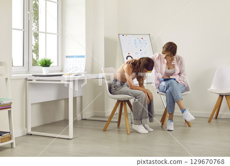 Sad, depressed, frustrated teenage girl talking with a therapist or psychologist 129670768