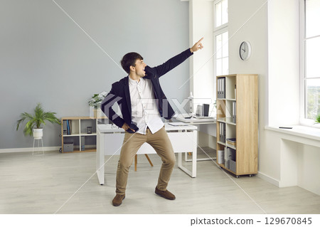 Young businessman is dancing happily enjoying his work and celebrating his success. 129670845
