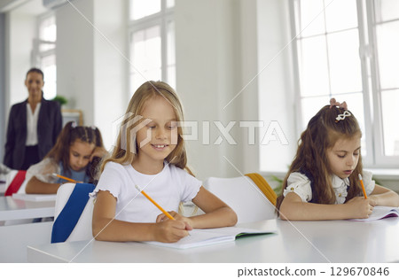 Elementary school children sitting in the classroom and writing in their notebooks Elementary school children sitting in the classroom and writing in their notebooks 129670846