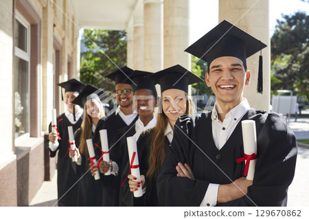 Photo of smiling college graduates standing behind each other 129670862