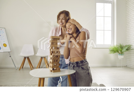Happy teenage girl having play therapy with her loving mother or friendly psychologist Happy teenage girl having play therapy with her loving mother or friendly psychologist 129670907