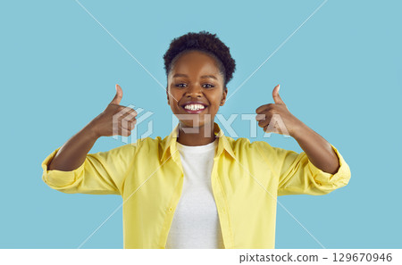 Joyful dark-skinned woman making thumb up sign showing her support and respect to you. 129670946