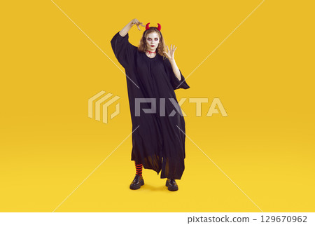 Woman in Halloween costume is scaring you with creepy serious look and waving her hands. Woman in Halloween costume is scaring you with creepy serious look and waving her hands. 129670962
