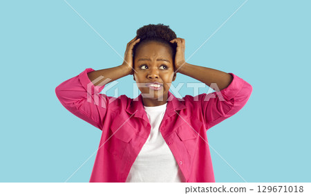 Funny woman who made mistake or forgot something grabs her head on light blue background. Funny woman who made mistake or forgot something grabs her head on light blue background. 129671018