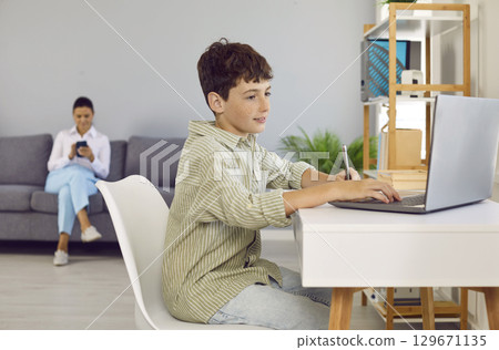 Child sitting at desk at home, doing homework and browsing Internet on laptop computer Child sitting at desk at home, doing homework and browsing Internet on laptop computer 129671135