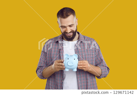 Happy handsome young man holding his piggy bank 129671142