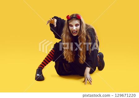 Scary woman with open mouth dressed as devil for Halloween crawling and trying to catch somebody. 129671220