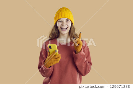 Happy woman with mobile phone raising her index finger mentioning good mobile offer, app or website Happy woman with mobile phone raising her index finger mentioning good mobile offer, app or website 129671288