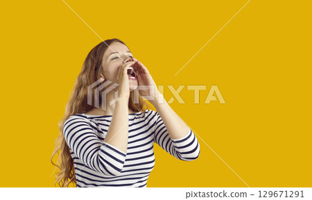 Woman in vest screams into mouthpiece folded from two hands indoor studio shot isolated on orange background Woman in vest screams into mouthpiece folded from two hands indoor studio shot isolated on orange background 129671291