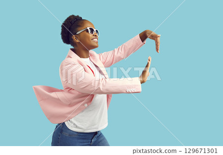 Cheerful stylish young African American woman dancing isolated on a blue background 129671301