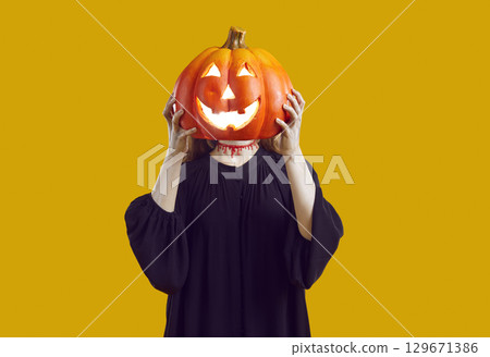 Unrecognizable woman with bloody cut on her neck hides her face behind glowing Halloween pumpkin. 129671386