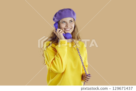 Girl in grandmothers beret with receiver of old wired telephone. 129671437