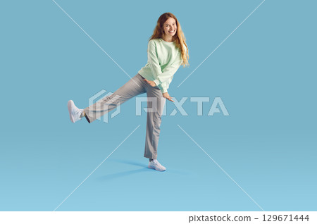 Cheerful positive young woman in good mood, having fun on light blue background. Cheerful positive young woman in good mood, having fun on light blue background. 129671444