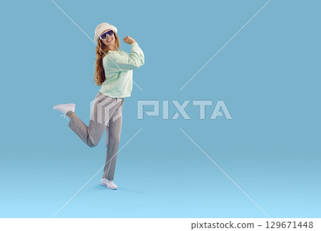 Laughing woman in white fluffy hat and sunglasses on blue background with copy space. Laughing woman in white fluffy hat and sunglasses on blue background with copy space. 129671448