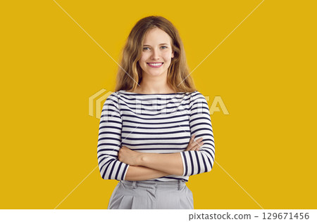 Portrait of happy beautiful young woman in striped top isolated on orange yellow background 129671456