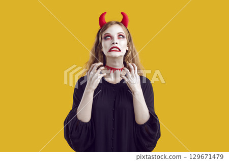 Displeased woman in Halloween costume makes annoyed grimace on her face and raises her hands. Displeased woman in Halloween costume makes annoyed grimace on her face and raises her hands. 129671479