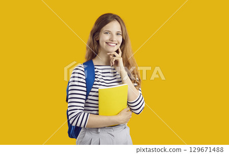 Portrait of happy girl student who is ready to study posing with backpack and schoolbook. Portrait of happy girl student who is ready to study posing with backpack and schoolbook. 129671488