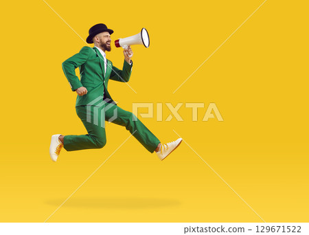 Man with megaphone jumps on copy space background and makes announcement about Patrick's Day party 129671522