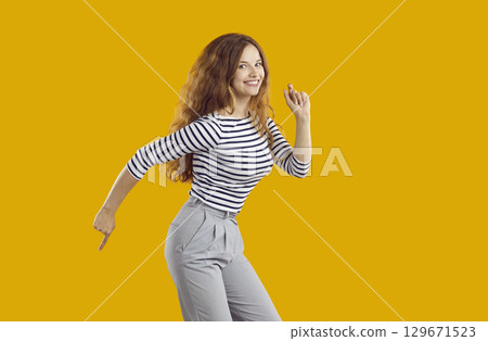 Funny young woman in great mood having fun doing dance moves on orange background. Funny young woman in great mood having fun doing dance moves on orange background. 129671523