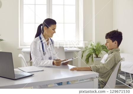 Caring female pediatrician talking with boy patient at consultation in hospital Caring female pediatrician talking with boy patient at consultation in hospital 129671530