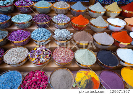 Traditional spices market. Pots and wooden tubs stand in row with colorful tea, spices, fruits, roots, flowers. Street bazaar. Dubai, UAE. Top view 129671567