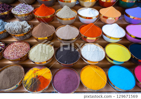 Traditional spices market. Pots and wooden tubs stand in row with colorful tea, spices, fruits, roots, flowers. Street bazaar. Dubai, UAE. Top view 129671569