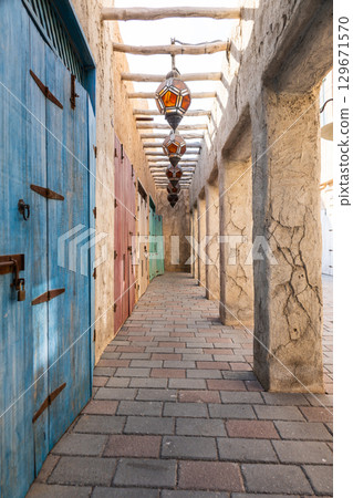 Old town in Al Seef Cultural Historical District on shores of Dubai Creek. Tourist place with old streets, houses and shops, Dubai, UAE. Vertical photo 129671570