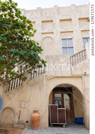Old town in Al Seef Cultural Historical District on shores of Dubai Creek. Tourist place with old streets, houses and shops, Dubai, UAE. Vertical photo 129671573