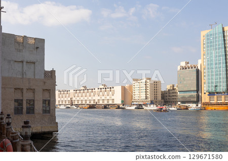 Old town in Al Seef Cultural Historical District. Beautiful view of water, old houses and new ones of Dubai Creek, Dubai, UAE. Taken off hand. High quality photo 129671580