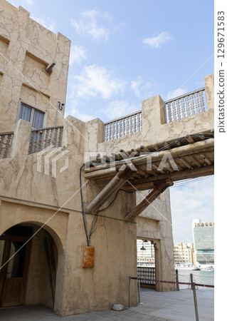 Old town in Al Seef Cultural Historical District on shores of Dubai Creek. Tourist place with old streets, houses and shops, Dubai, UAE. Vertical photo 129671583