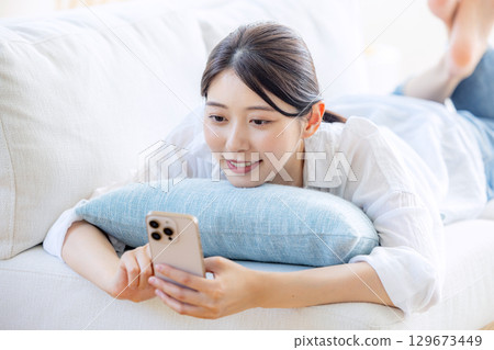 A woman watching a video in the living room A woman watching a video in the living room 129673449