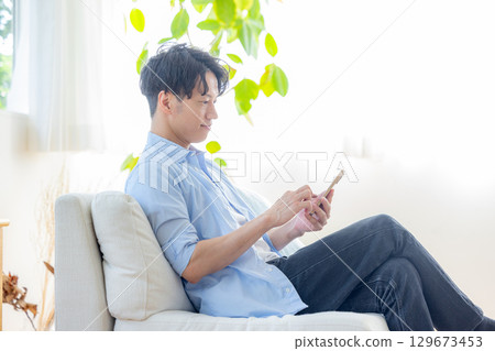 一個在客廳裡使用智能手機的人 129673453