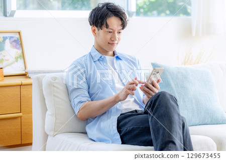 一個在客廳裡使用智能手機的人 129673455