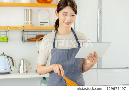 Woman standing in kitchen with tablet 129673497