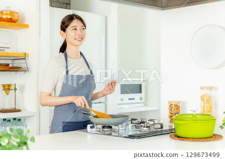 Woman standing in kitchen with tablet 129673499