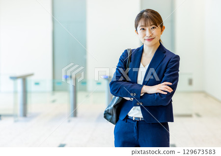 A young woman in a suit walking through an office lobby 129673583