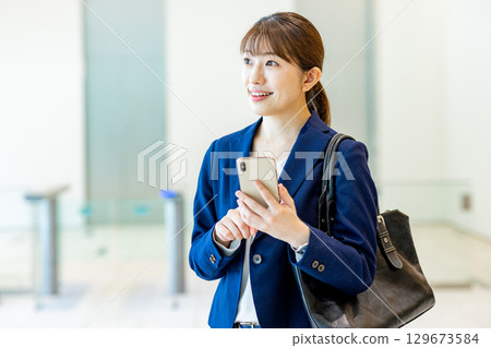 A young woman in a suit walking through an office lobby 129673584