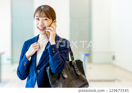 A young woman in a suit walking through an office lobby 129673585