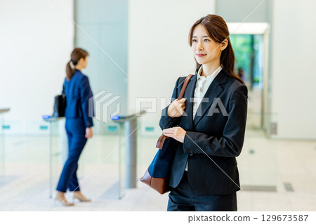 A young woman in a suit walking through an office lobby A young woman in a suit walking through an office lobby 129673587