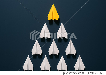 A yellow airplane at the top of a black triangle of airplanes symbolizing leadership dominance and strength 129675168