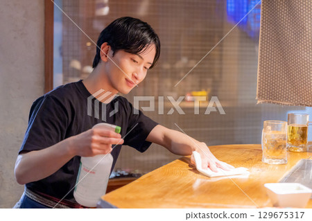 Izakaya: Female staff serving drinks to customers 129675317