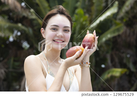 Beautiful woman holding a mango 129675529