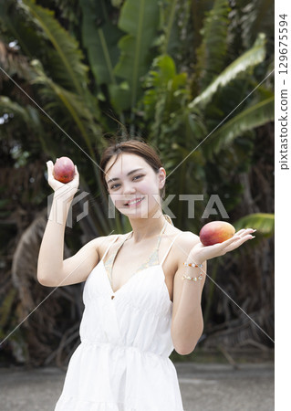 Beautiful woman holding a mango 129675594