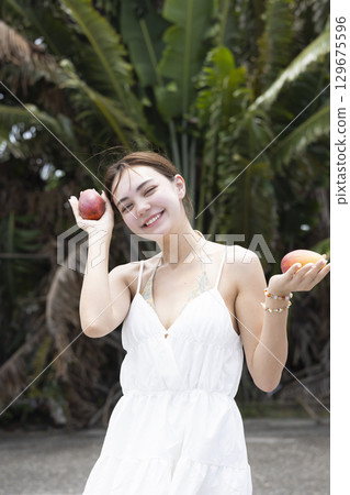 Beautiful woman holding a mango 129675596