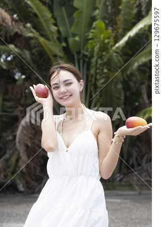 Beautiful woman holding a mango Beautiful woman holding a mango 129675597