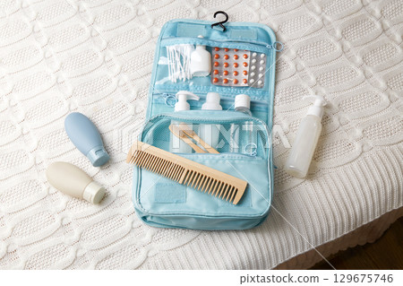 A travel set of toiletries is neatly laid out on a white blanket in a hotel.  129675746