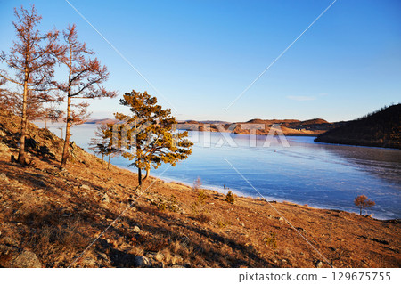Lake Baikal in December. View of the frozen Kurkut Bay in the rays Lake Baikal in December. View of the frozen Kurkut Bay in the rays 129675755