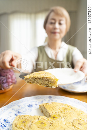A senior woman baking a cake and making tea to enjoy her own time 129675904
